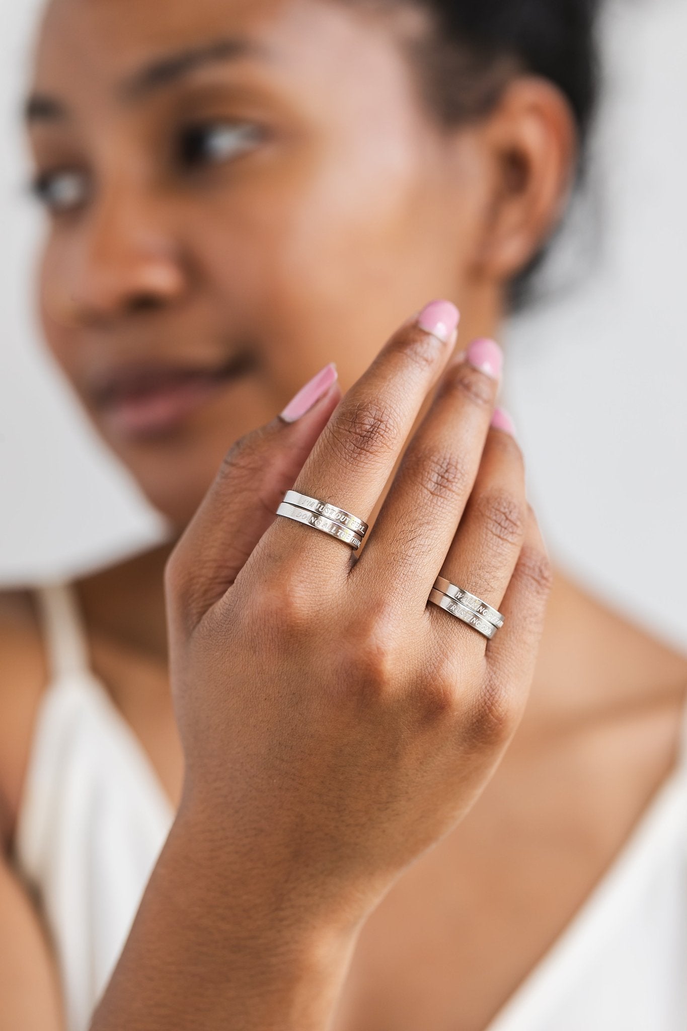Close-up of two fingers adorned with silver faith-based statement rings stacked from the Faith Reflections Ring Set by A Meaningful Mood.