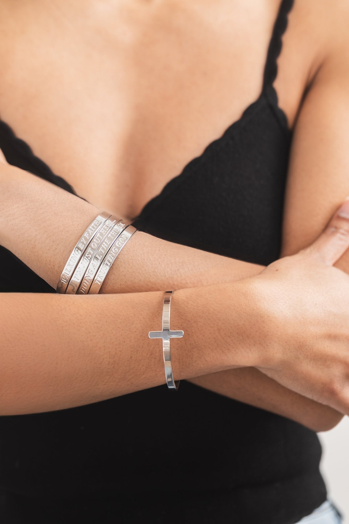 Christian stainless steel engraved scripture bracelets and a cross cuff, styled on wrist for faith-inspired fashion.