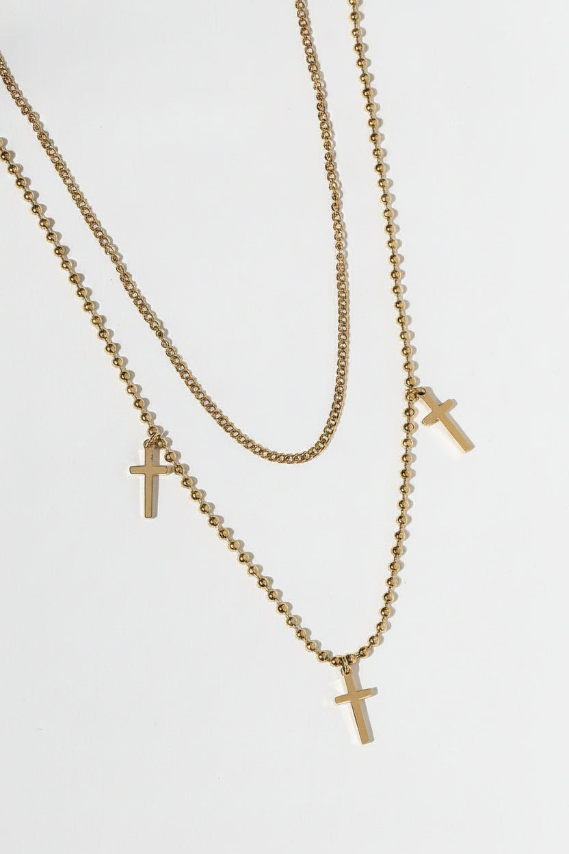 Flat lay of So Chic Cross Layered Necklace featuring 3 gold cross pendants on tiered chains