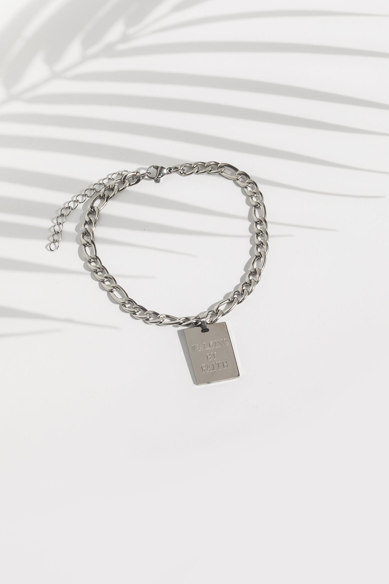 Flat lay of the Walking By Faith pendant anklet in stainless steel from A Meaningful Mood, featuring a bold Cuban link chain and engraved Christian message, perfect for everyday faith-filled fashion and durable Christian jewelry style.
