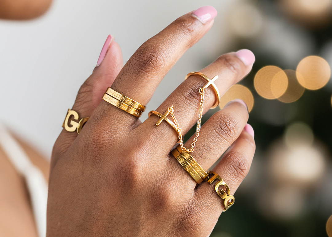 Hand wearing multiple gold rings with a blurred background