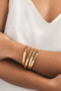 Woman wearing 4 stacked engraved gold bangles on her wrist – stylish & meaningful Christian faith jewelry for everyday wear.