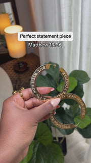 Close-up of woman holding large 18k gold plated hoop earring engraved with “But With God All Things Are Possible” — bold Christian statement earrings by A Meaningful Mood for faith-filled fashion.