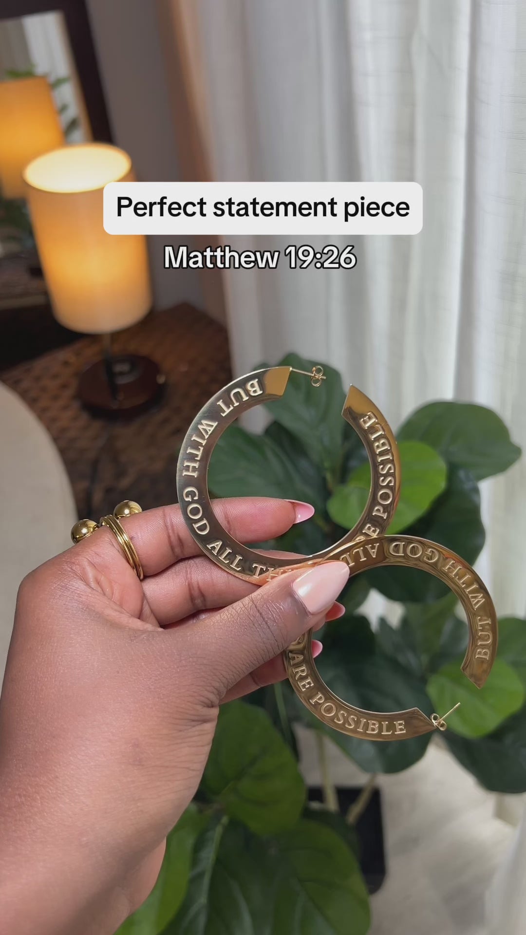 Close-up of woman holding large 18k gold plated hoop earring engraved with “But With God All Things Are Possible” — bold Christian statement earrings by A Meaningful Mood for faith-filled fashion.
