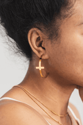 Detailed ear view of A Meaningful Mood’s So Chic Cross Hoops in 18k gold plated stainless steel. Minimalist cross earrings designed to express Christian faith with timeless, stylish elegance.