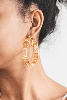 Close-up of woman wearing large gold Trust God Hoop Earrings – faith-inspired Christian jewelry.