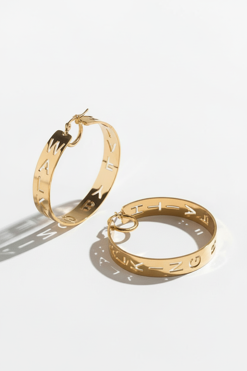 Pair of gold statement hoop earrings with cutout design featuring "Walking by Faith" displayed on a white surface. Christian jewelry by A Meaningful Mood.